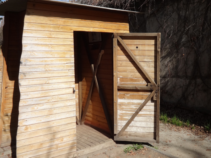 Wooden shack in front of mosaic stone sign